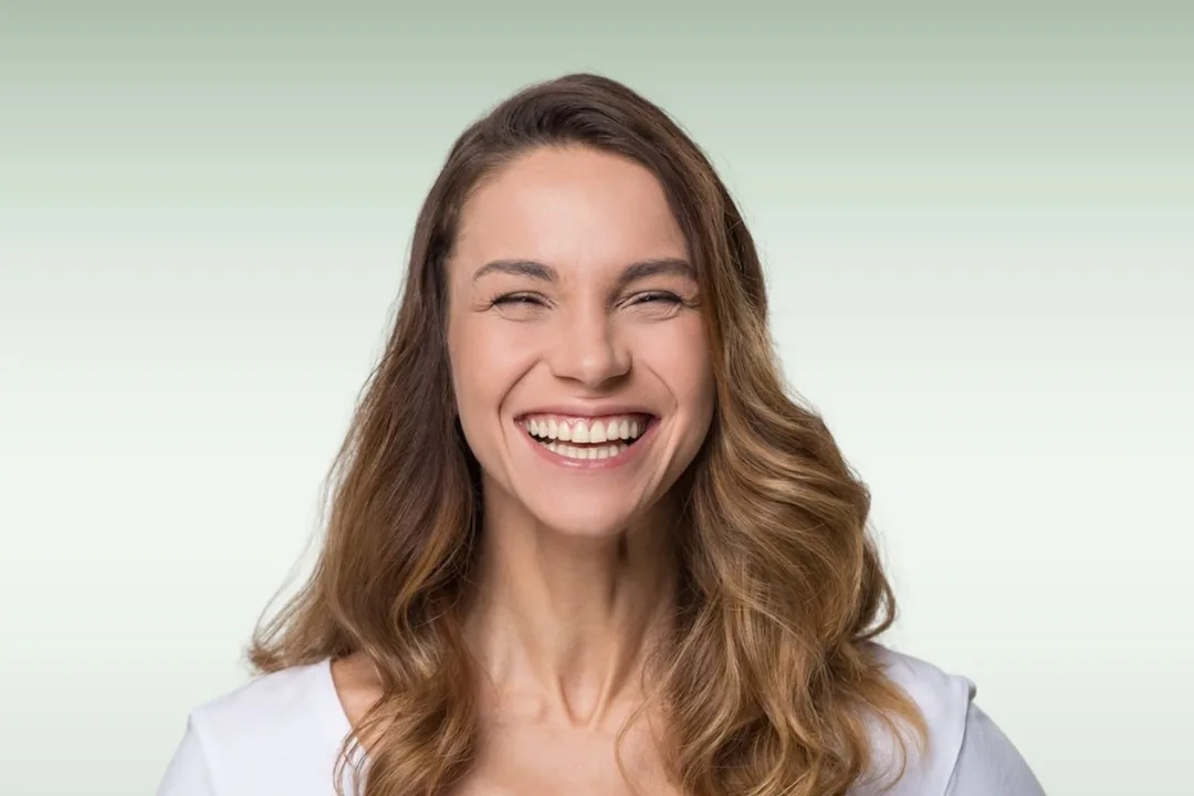 A dental crown being compared against a shade guide to match a natural tooth