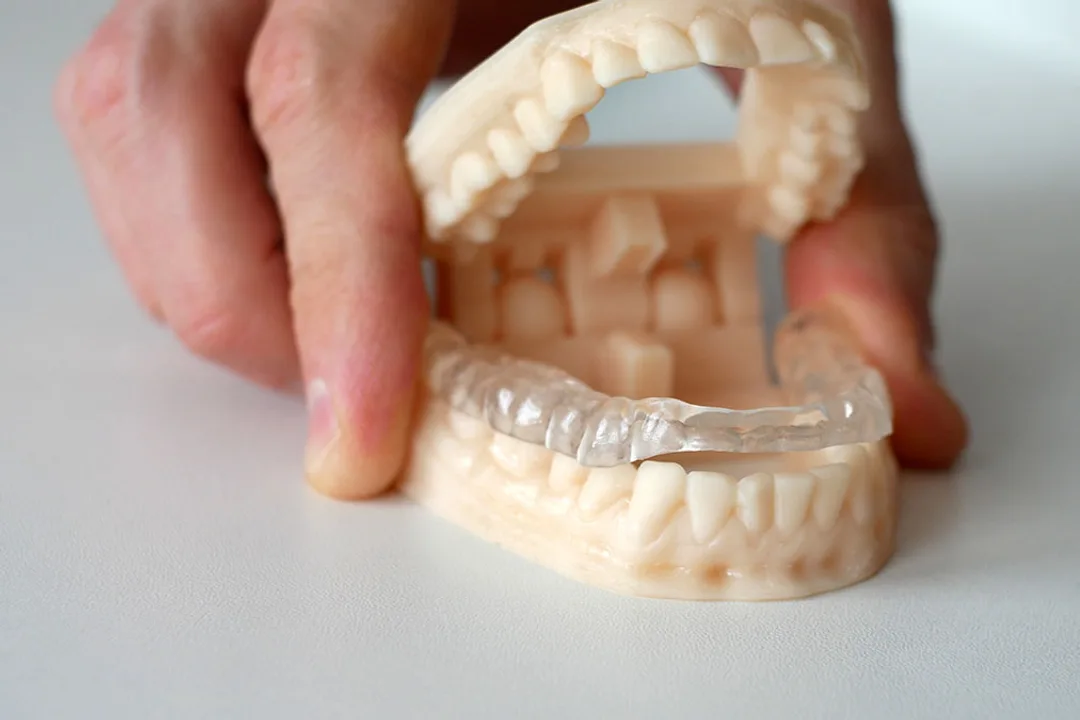 A dentist gently examining a patient’s jaw joint for signs of a TMJ disorder